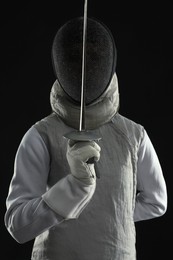 Photo of Fencer with epee on black background. Combat sport