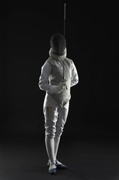 Fencer with epee on dark background. Combat sport