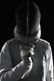 Fencer with epee on black background. Combat sport