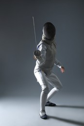 Photo of Fencer with epee practicing on gray background