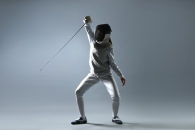 Photo of Fencer with epee practicing on gray background