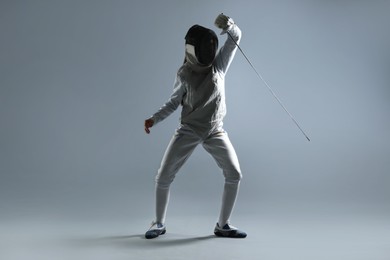 Photo of Fencer with epee practicing on gray background