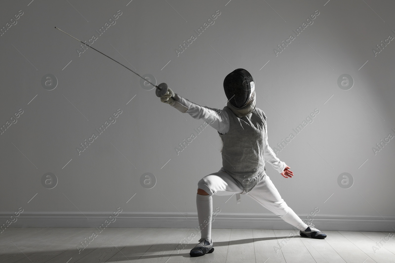 Photo of Fencer with epee practicing indoors. Combat sport