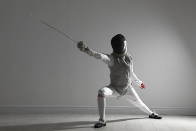 Photo of Fencer with epee practicing indoors. Combat sport