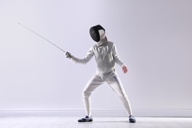 Fencer with epee practicing indoors. Combat sport