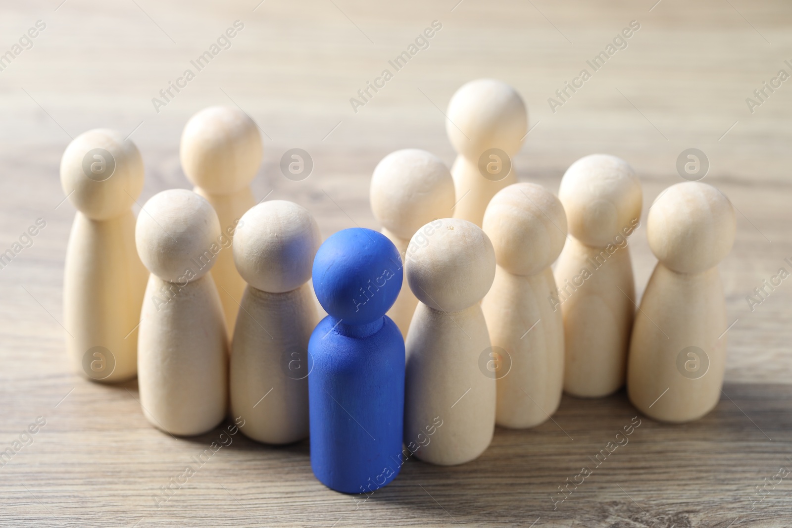 Photo of Human resources concept. Blue figure among wooden ones on table, closeup