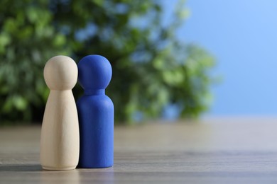 Photo of Human resources concept. Blue and wooden figures on table against blurred background, closeup. Space for text