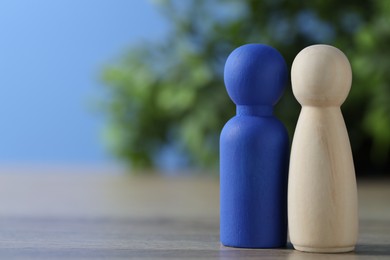 Photo of Human resources concept. Blue and wooden figures on table against blurred background, closeup. Space for text