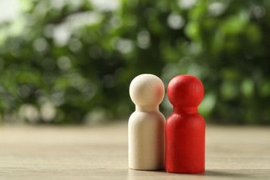 Photo of Human resources concept. Red and wooden figures on table against blurred background, closeup. Space for text