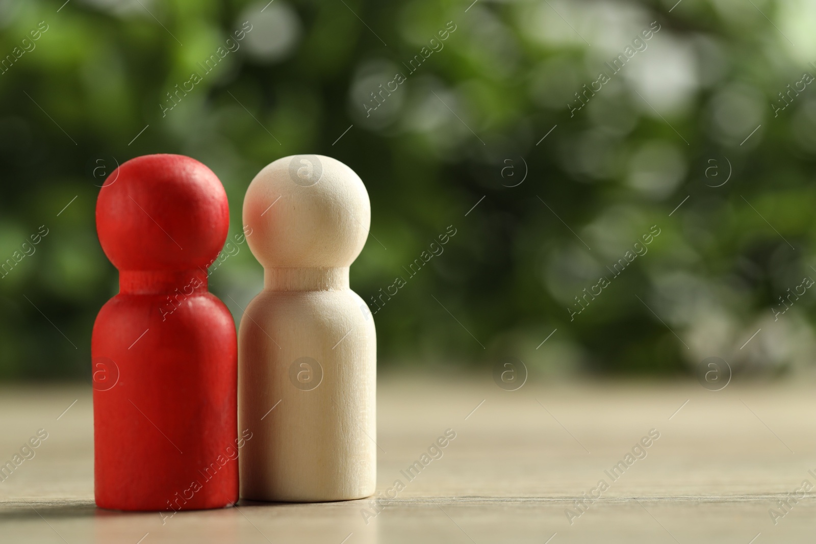 Photo of Human resources concept. Red and wooden figures on table against blurred background, closeup. Space for text