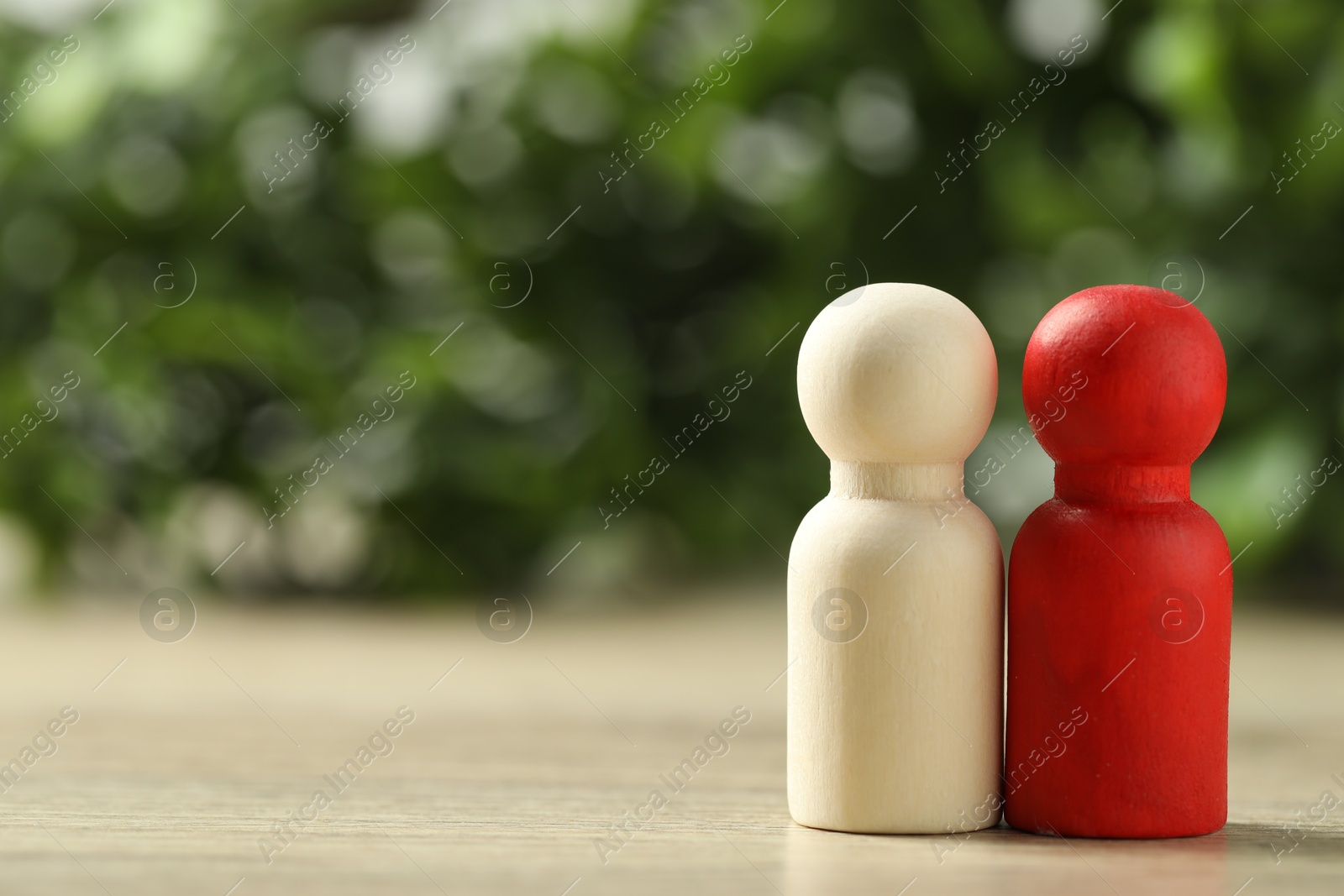 Photo of Human resources concept. Red and wooden figures on table against blurred background, closeup. Space for text