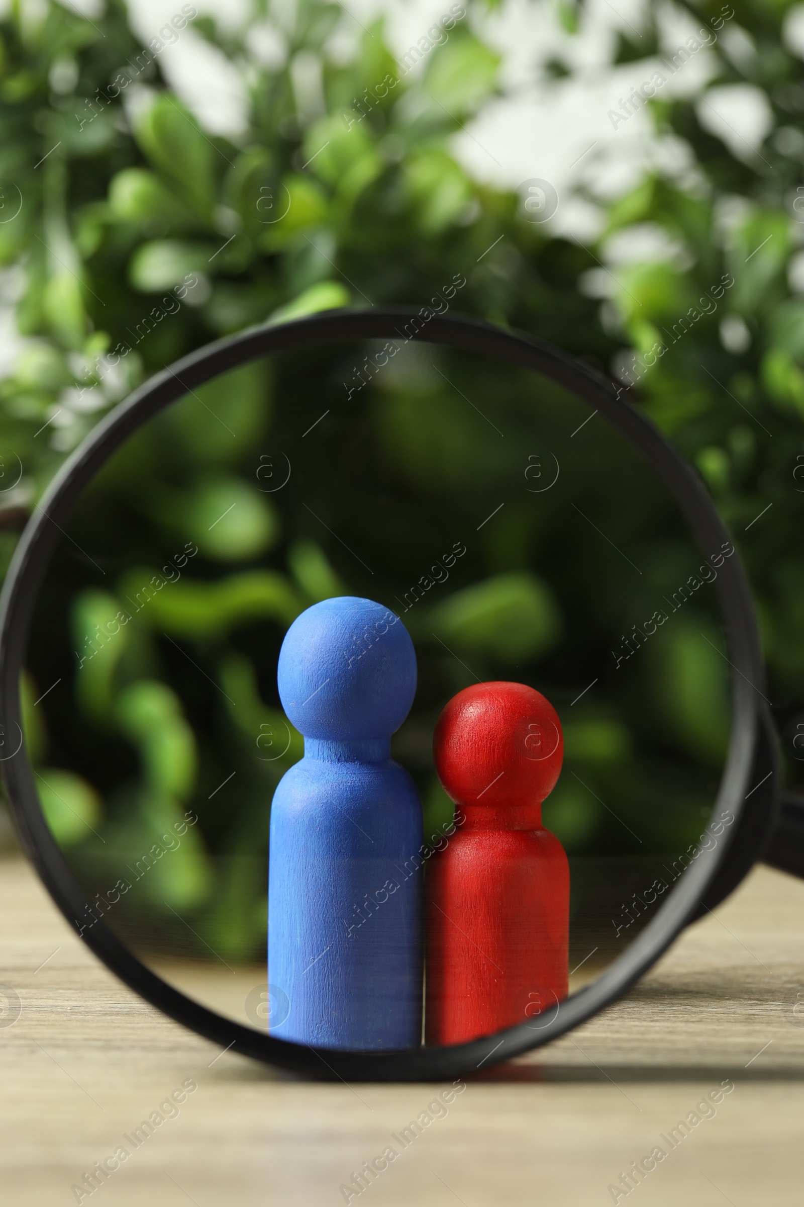 Photo of Human resources concept. Looking at color figures through magnifying glass on wooden table against blurred background, closeup