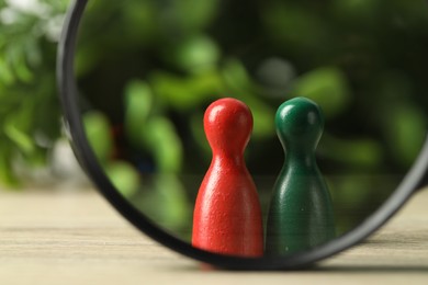 Photo of Human resources concept. Looking at color figures through magnifying glass on wooden table against blurred background, closeup