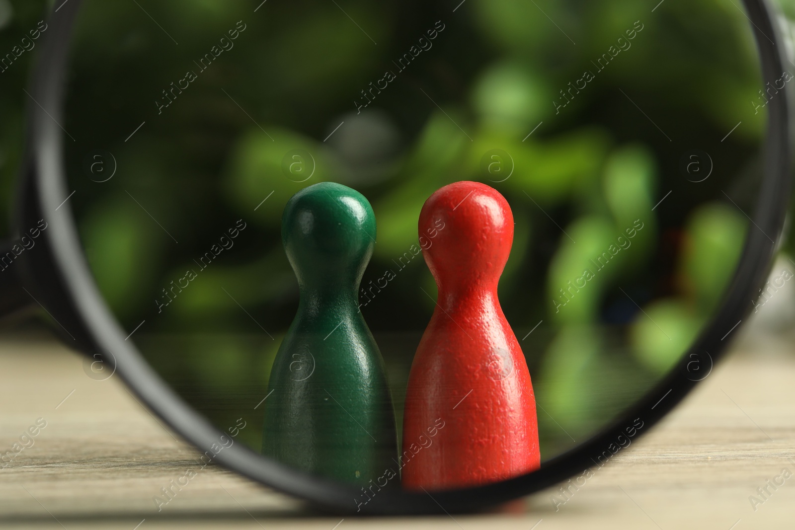 Photo of Human resources concept. Looking at color figures through magnifying glass on wooden table against blurred background, closeup