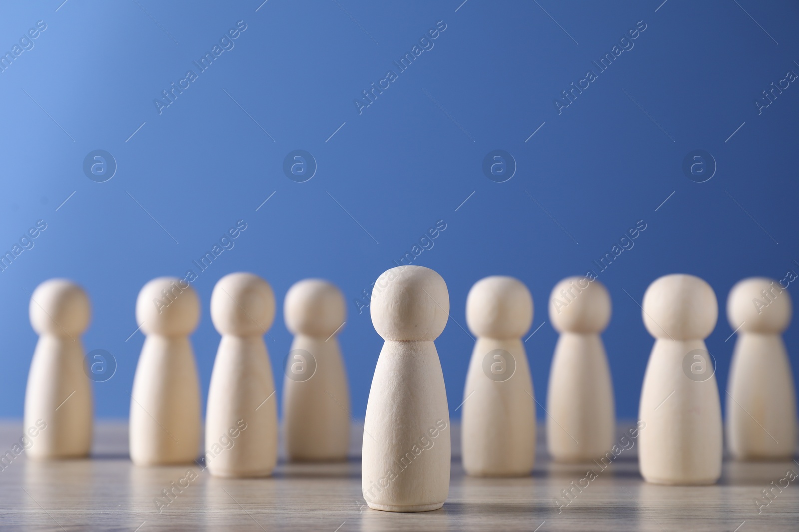 Photo of Human resources concept. Many wooden figures on table against blue background, closeup. Space for text