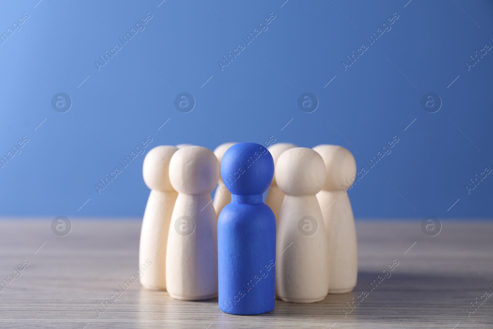 Photo of Human resources concept. Blue figure among wooden ones on table, closeup. Space for text