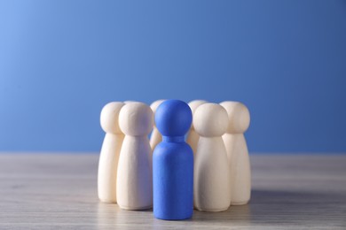 Photo of Human resources concept. Blue figure among wooden ones on table, closeup. Space for text