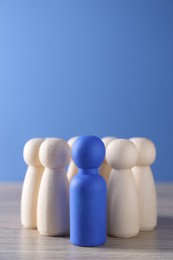 Photo of Human resources concept. Blue figure among wooden ones on table, closeup. Space for text