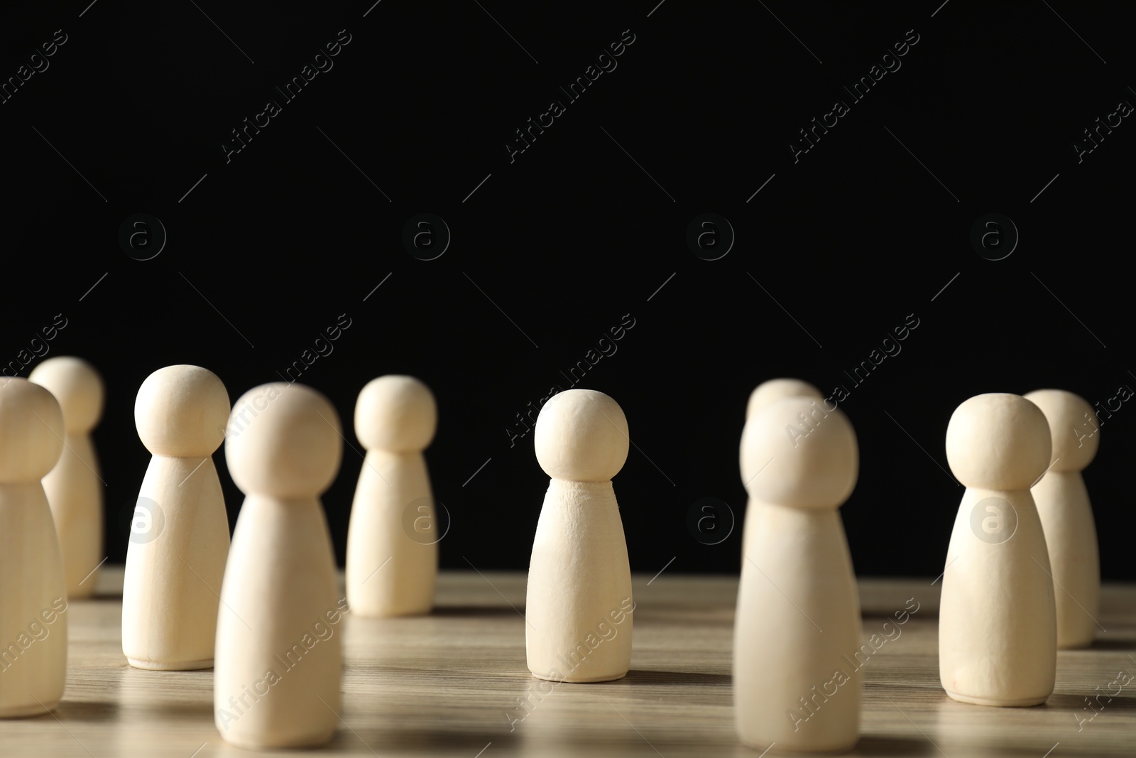 Photo of Human resources concept. Many wooden figures on table against dark background, closeup. Space for text