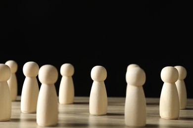 Photo of Human resources concept. Many wooden figures on table against dark background, closeup. Space for text