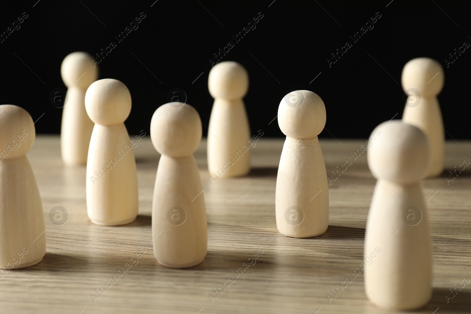 Photo of Human resources concept. Many wooden figures on table against dark background, closeup