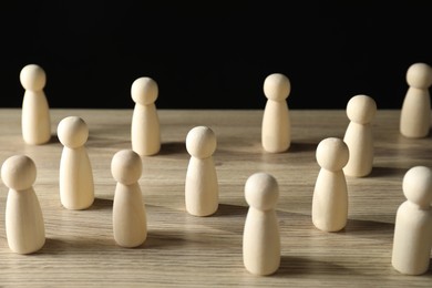 Photo of Human resources concept. Many wooden figures on table against dark background, closeup