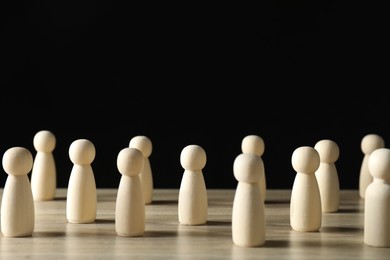 Photo of Human resources concept. Many wooden figures on table against dark background, closeup. Space for text