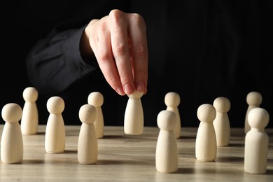 Photo of Human resources concept. Woman choosing wooden piece between other ones at table, closeup