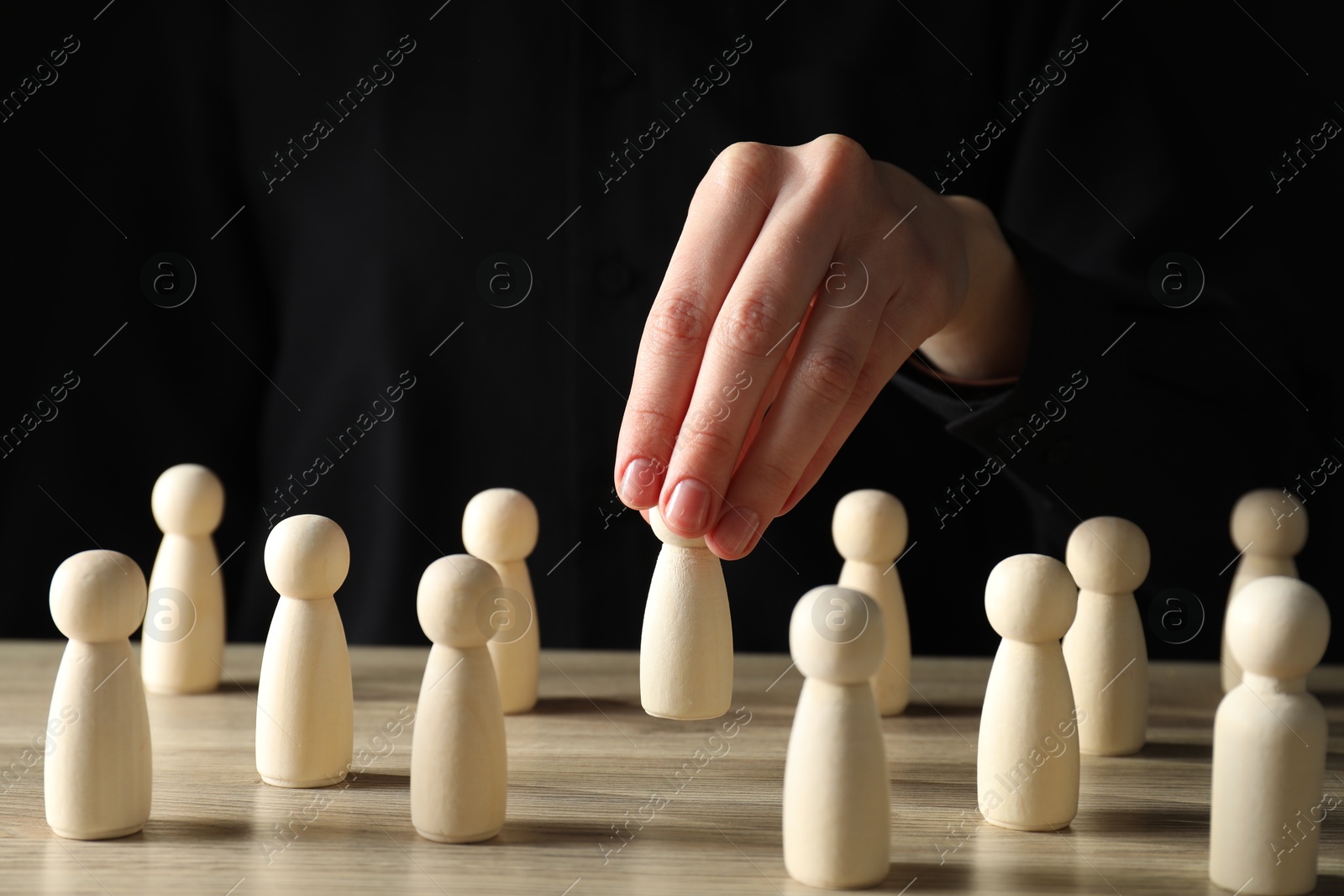 Photo of Human resources concept. Woman choosing wooden piece between other ones at table, closeup