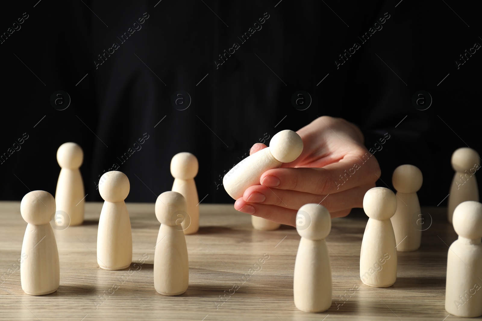 Photo of Human resources concept. Woman choosing wooden piece between other ones at table, closeup