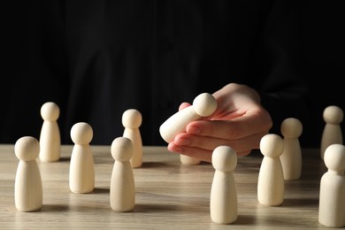 Photo of Human resources concept. Woman choosing wooden piece between other ones at table, closeup