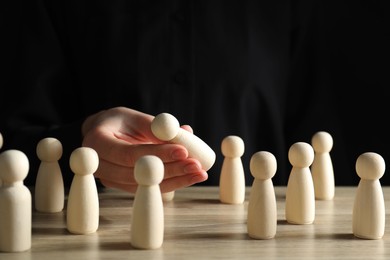 Photo of Human resources concept. Woman choosing wooden piece between other ones at table, closeup