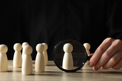 Photo of Human resources concept. Woman with magnifying glass and wooden pieces at table, closeup