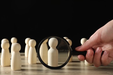 Photo of Human resources concept. Woman with magnifying glass and wooden pieces at table, closeup. Space for text