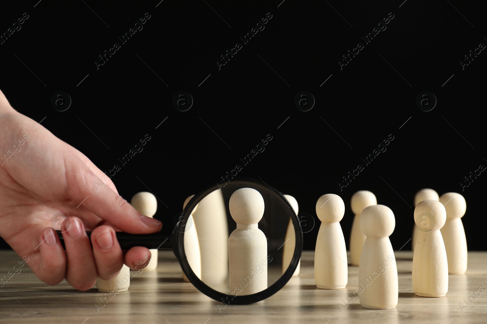 Photo of Human resources concept. Woman with magnifying glass and wooden pieces at table, closeup. Space for text