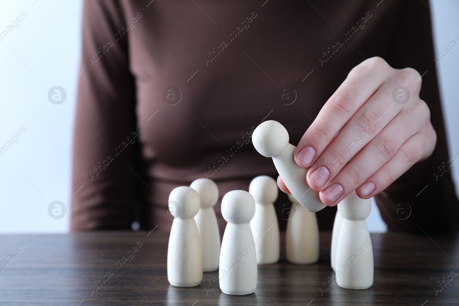 Photo of Human resources concept. Woman choosing wooden piece between other ones at table, closeup