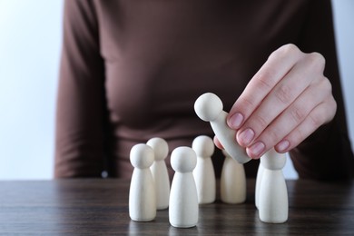 Photo of Human resources concept. Woman choosing wooden piece between other ones at table, closeup