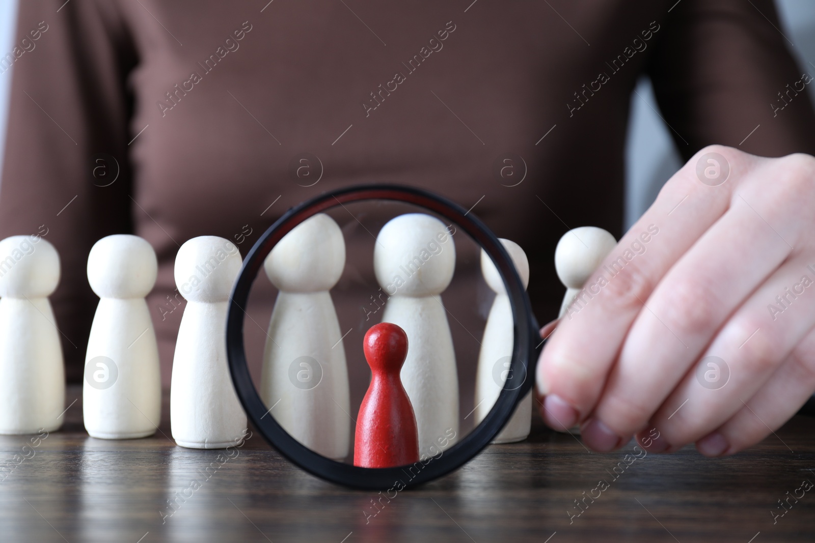 Photo of Human resources concept. Woman with magnifying glass and wooden pieces at table, closeup