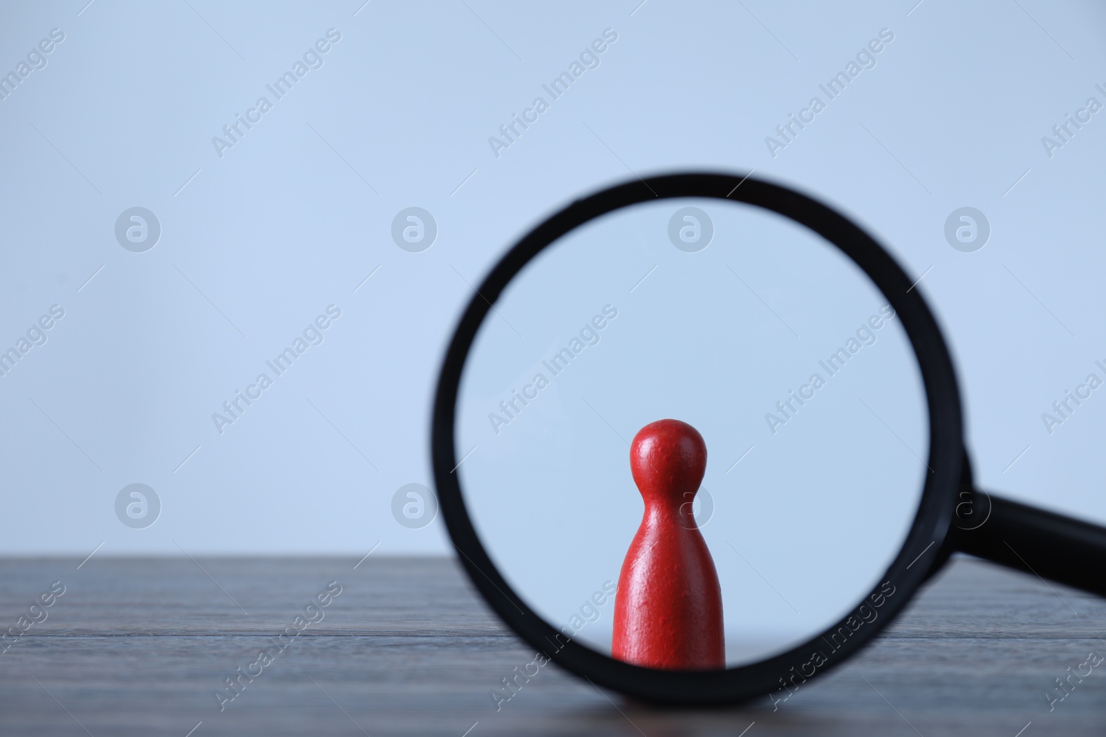 Photo of Human resources concept. Looking at red figure through magnifying glass on table against light background, closeup. Space for text