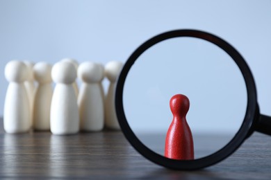 Photo of Human resources concept. Looking at red figure through magnifying glass on table against light background, closeup