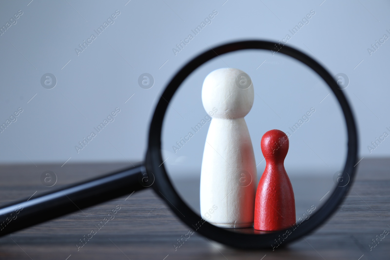 Photo of Human resources concept. Looking at wooden figures through magnifying glass on table against light background, closeup. Space for text