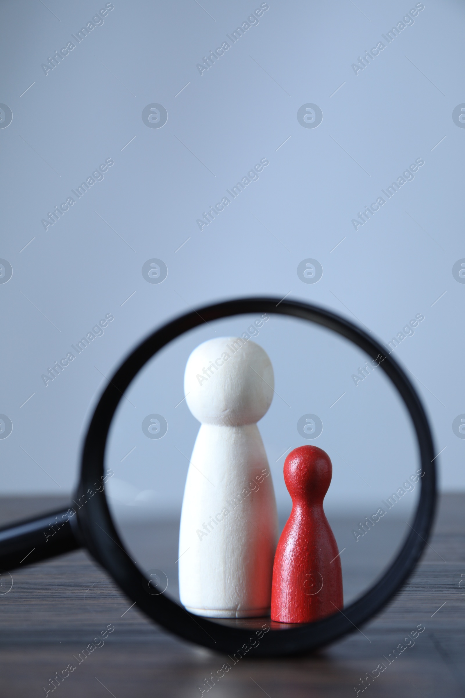 Photo of Human resources concept. Looking at wooden figures through magnifying glass on table against light background, closeup