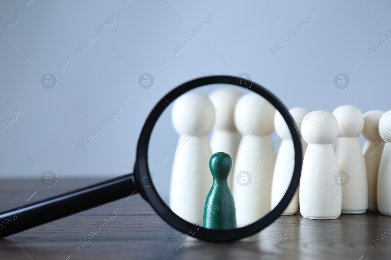 Photo of Human resources concept. Looking at green figure through magnifying glass on table against light background, closeup. Space for text