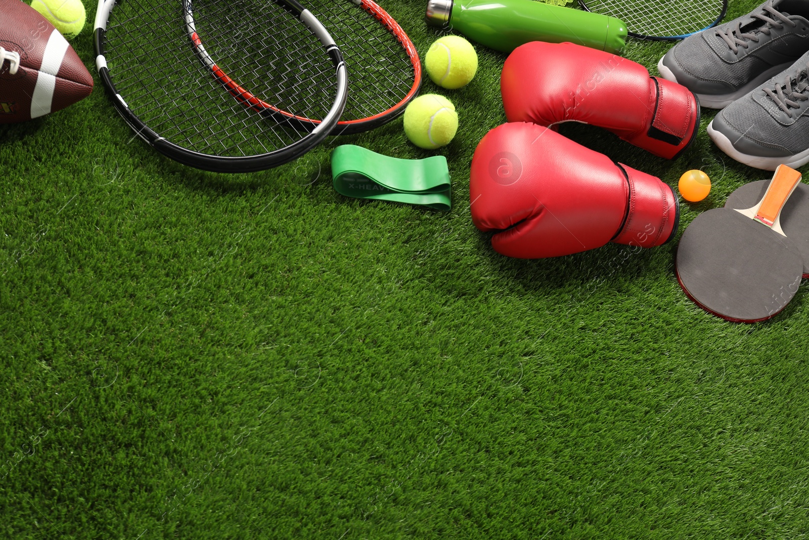 Photo of Different sport equipment on artificial grass, above view. Space for text