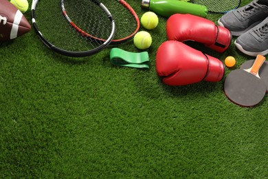 Photo of Different sport equipment on artificial grass, above view. Space for text