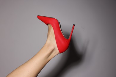 Photo of Woman wearing beautiful red high heeled shoes on light grey background, closeup