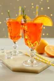 Photo of Tasty Christmas cocktail in glasses on white wooden table against blurred lights