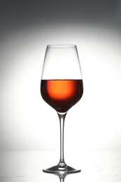 Tasty wine in glass on light background