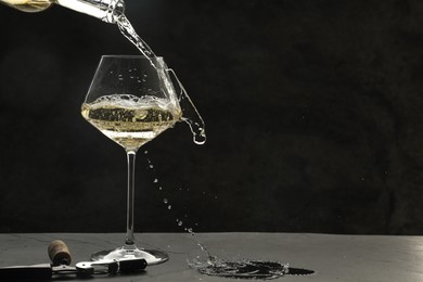 Photo of Pouring white wine into glass at grey table, space for text