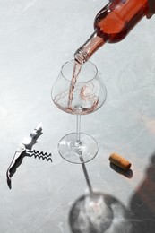 Photo of Pouring rose wine into glass at grey marble table